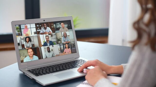 Young woman using a laptop computer for video connection with diverse group of people, female involved video conference with multiracial team, a lot of colleagues profiles on the display