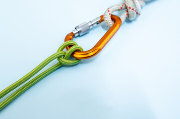 Orange carabiner. Equipment for climbing and mountaineering. Safety rope. Knot Prusik, clove hitch. Isolated on the blue background.
