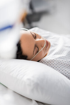 sick african american woman with nasal cannula sleeping in hospital on blurred foreground