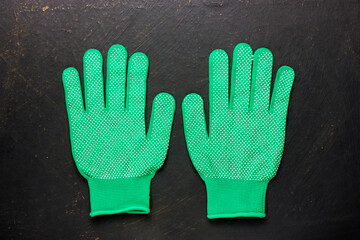 Two green work gloves on a black background. Gardening gloves. A pair of gloves.