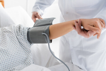 cropped view of doctor putting tonometer cuff on hand of woman