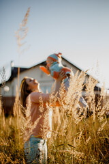 Happy woman with a child in a wheat field. Happy mother holding baby smiling on a wheat field in sunlight. Family happiness concept.