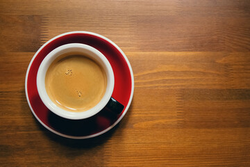 Red cup of coffee on wooden table as a background. Flat lay style. Top view. Copy space