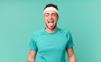 fitness man with cheerful, carefree, rebellious attitude, joking and sticking tongue out, having fun