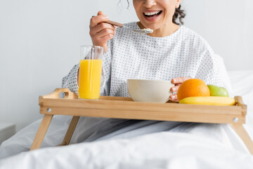 cropped view of smiling african american woman having breakfast in hospital on blurred foreground