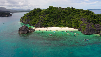 Obraz premium Tropical landscape: Lahos Island with beautiful beach and tourists by turquoise water view from above. Caramoan Islands, Philippines. Summer and travel vacation concept.
