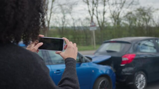 Female Driver Taking Photos Of Road Traffic Accident On Mobile Phone For Insurance Claim