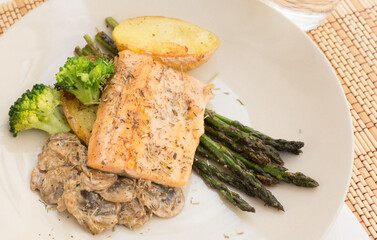 dish of fried river trout fillet with garnish of broccoli, asparagus sprouts and mushroom sauce