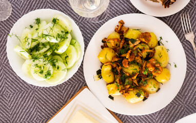 baked potatoes with chanterelles, served with herbs on white plate