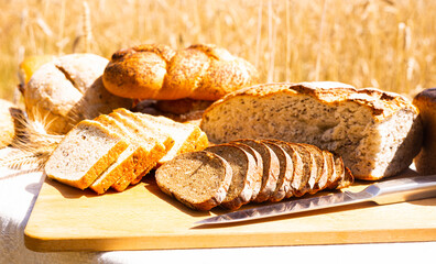 lot of different flavored bread, wheat, rye, on the table in the field outside