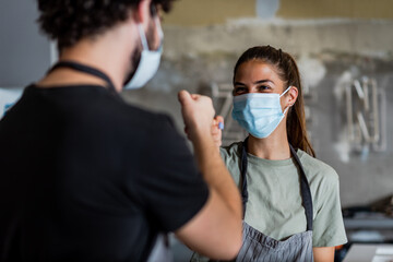 Obraz na płótnie Canvas Team work spirit.Millennial business team wear protective masks, posing in coffee shop during corona virus.