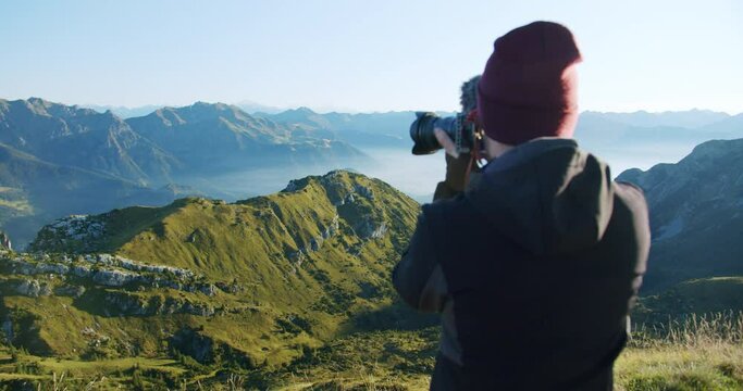 A young man photographs the mountains during a sunrise