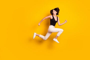 Fototapeta na wymiar Full length body size side profile photo of crazy woman jumping running away looking back isolated bright yellow color background