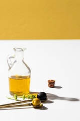 Virgin  olive oil  bottle,  black and green olives in gold spoonl on white background. Hard light with shadow.