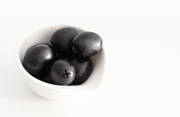 Black olive fruit in white bowl.