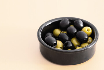 Mix of black and green olive in dark ceramic bowl