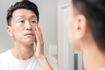 A man looks checks the condition of his skin