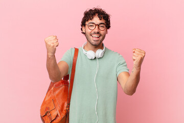 hispanic student feeling shocked, excited and happy, laughing and celebrating success, saying wow!
