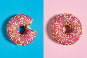 Creative food diet concept photo of donut bite on pink blue background.