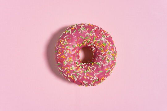 Creative food diet concept photo of donut bite on pink  background.