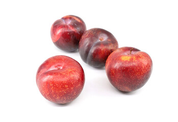 Fototapeta na wymiar Four large red plums with little yellow dots on white background