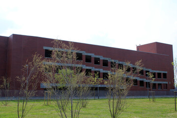 Fototapeta premium Edificio industriale e parcheggio sopraelevato con prato e alberi