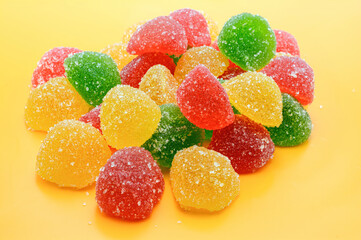 Colored jelly sweet candies or marmalade, isolated on a yellow background.