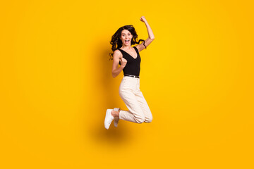 Fototapeta na wymiar Full length body size photo of girl funny jumping gesturing like winner overjoyed isolated on vibrant yellow color background