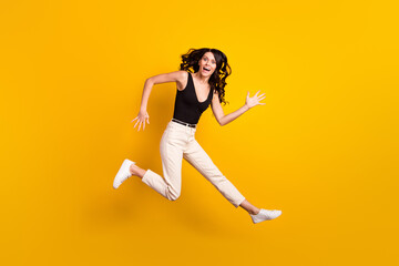 Fototapeta na wymiar Full length body size photo of girl funny jumping up laughing in casual clothes isolated on vivid yellow color background