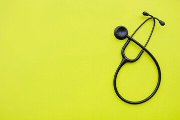 Black medical stethoscope on green background. Medicine and healthcare concept. Space for text....