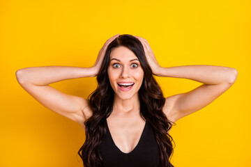 Photo of young excited girl happy positive smile amazed surprised sale news hands touch head isolated over yellow color background