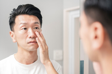 A man looks checks the condition of his skin