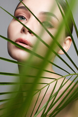 Naklejka premium beautiful girl in palm leaves. Beautiful young woman with Make-up