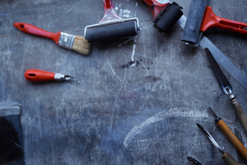 Linocut tools concept. Working tools in red and black colors on dark table with copy space. Cutting instruments, ink roller and other tools for linocut making. High quality photo