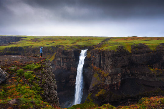 Hiker standing at the edge of the Haifoss waterfall in Iceland