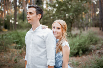 Obraz premium Happy young couple on a walk in the forest at sunset. The bride is wearing a blue wedding dress.