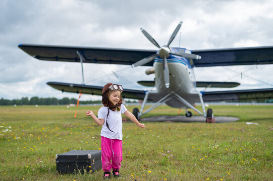 A cute little girl playing on the field by a four-seater private jet dreaming of becoming a pilot