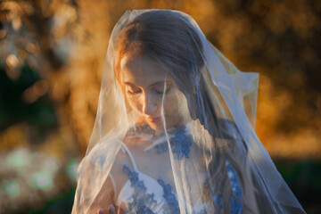 Happy bride in a blue dress laughs at sunset in the forest.