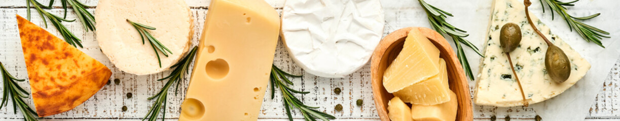Set or assortment cheeses. Suluguni with spice, camembert, blue cheese, parmesan, maasdam, brie cheese with rosemary and pepper.  Top view. On white wooden old background. Free copy space.
