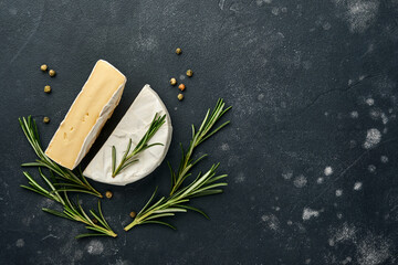 Pieces camembert cheese with rosemary, capers and pepper. On black old background. Top view. Free...