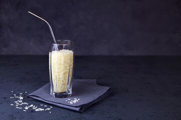 Rice in a glass with a metal tube for drinks. The concept of plant-based vegan milk.