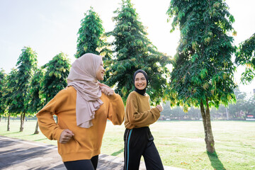 two girls in veil do outdoor sports while jogging together in the garden with copyspace