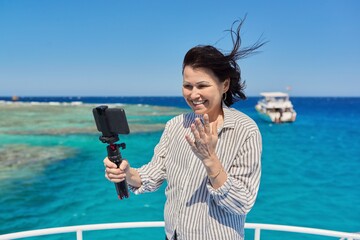 Happy woman recording video stream on smartphone, background is place for diving and snorkeling