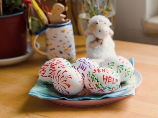 homemade send help sign painted easter eggs table setting with some other decorations and flowers in the background on wooden table in the kitchen