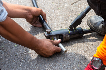Fototapeta premium Close-up of electricians' equipment To clamp the metal to connect the largely broken wires Using a metal pipe, electrical insulation is plugged into the broken wire using a large clamp.