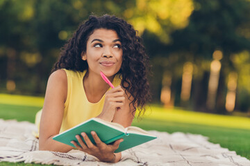 Portrait of attractive dreamy cheerful girl lying on duvet writing idea plan to-to list studying on fresh air outdoor