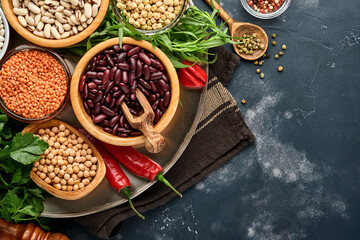 Legumes, lentils, chickpea, beans assortment, tasty appetizing ingredients spices grocery for cooking healthy kitchen on black table. Weight loss diet and fight against cholesterol concept. Top view.