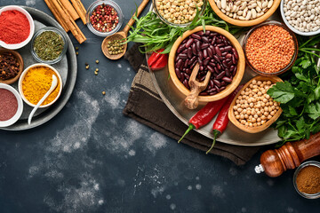 Legumes, lentils, chickpea, beans assortment, tasty appetizing ingredients spices grocery for cooking healthy kitchen on black table. Weight loss diet and fight against cholesterol concept. Top view.