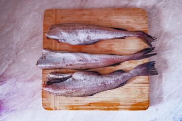 carcasses of raw pollock fish lie on the cutting board