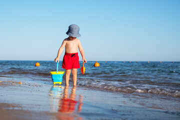 Boy kid in red shorts on the summer beach